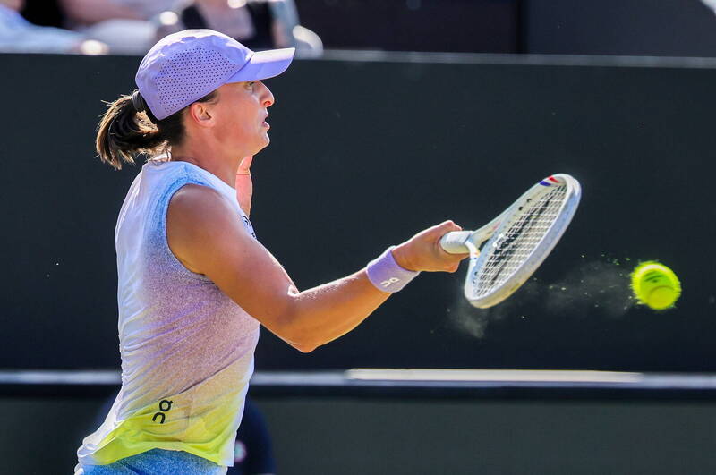 波蘭網球名將史薇泰克（Iga Swiatek）在草地賽場上揮拍擊球，專注投入比賽。