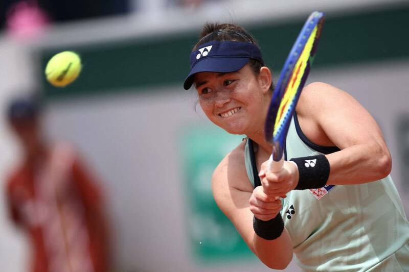 台灣網球選手葛藍喬安娜在草地賽事中專注揮拍回擊來球，面露堅毅表情，身穿無袖球衣與深色帽簷。