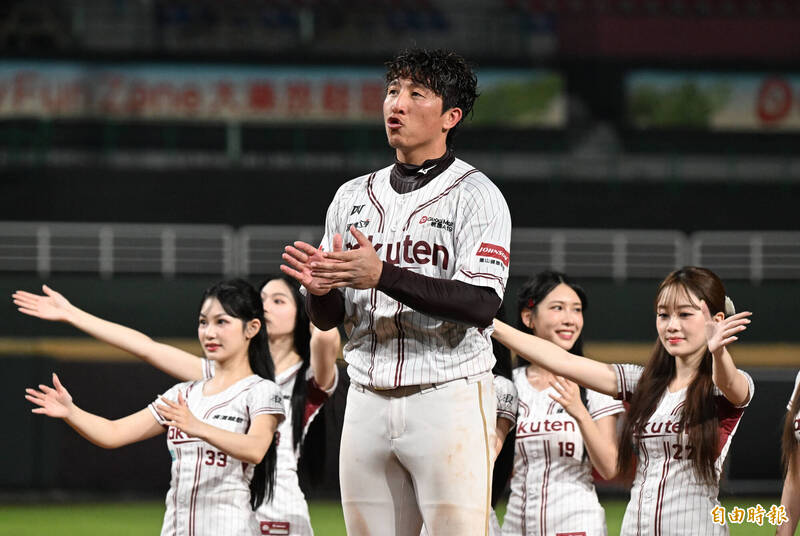 樂天桃猿球員成晉賽後站在場中央，身後是啦啦隊成員，一同為勝利鼓掌慶祝，展現勝利氣氛與團隊士氣。