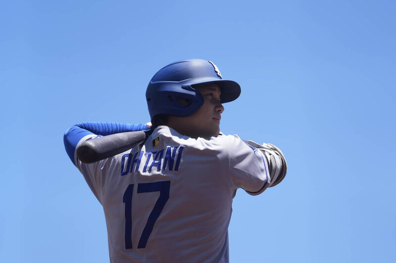 道奇球星大谷翔平揮棒練習，身穿17號球衣，藍天為背景。