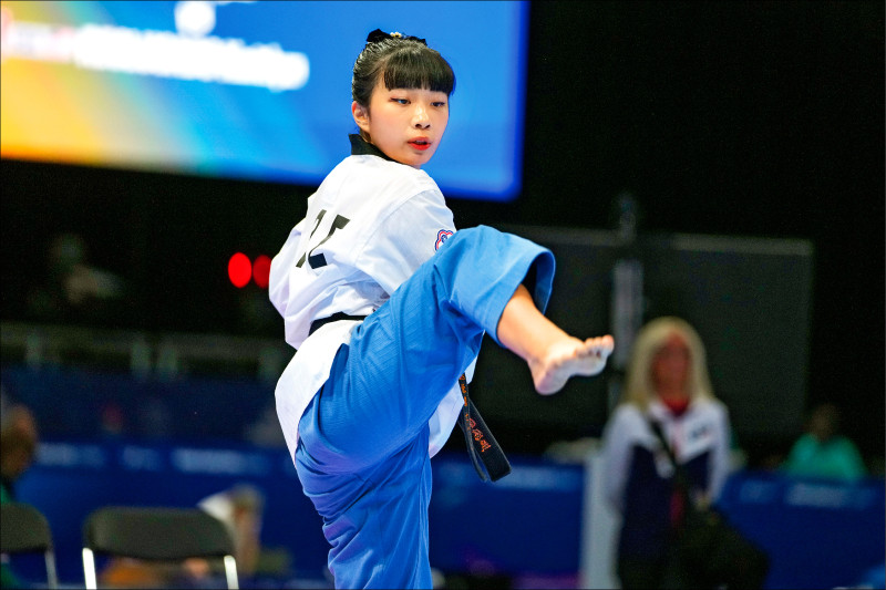 台灣跆拳道選手在世大運品勢比賽中高舉腿出腳，展現精準動作與專注神情。
