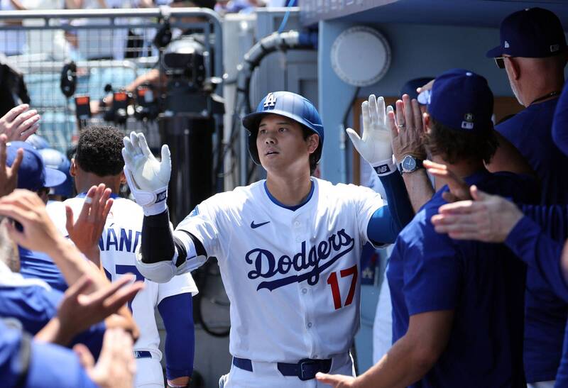 身穿洛杉磯道奇隊17號球衣的大谷翔平，在球員休息區與隊友擊掌慶祝全壘打後回到休息區。