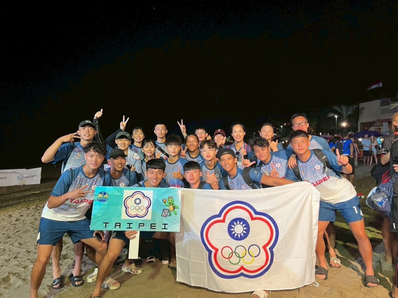台灣巧固球男女成人代表隊在印尼峇里島世界盃奪冠後合影留念，隊員手持中華台北會旗與自製應援牌，笑容洋溢於夜晚沙灘上。