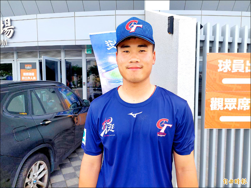 台灣U18世界盃棒球代表隊球員游能茗，身穿藍色中華隊訓練服與帽子，在球場外合影。
