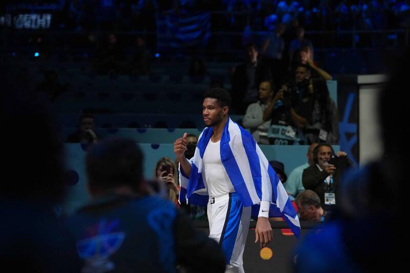 「希臘球星亞德托昆波身披國旗，賽後慶祝在歐錦賽奪下銅牌，場邊觀眾與媒體捕捉瞬間。」