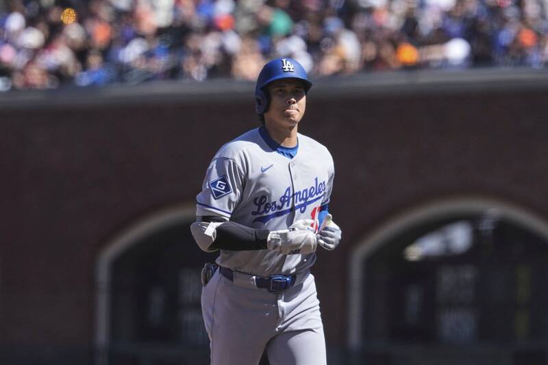 道奇隊日本球星大谷翔平在比賽中小跑步，身穿灰色客場球衣，神情專注。