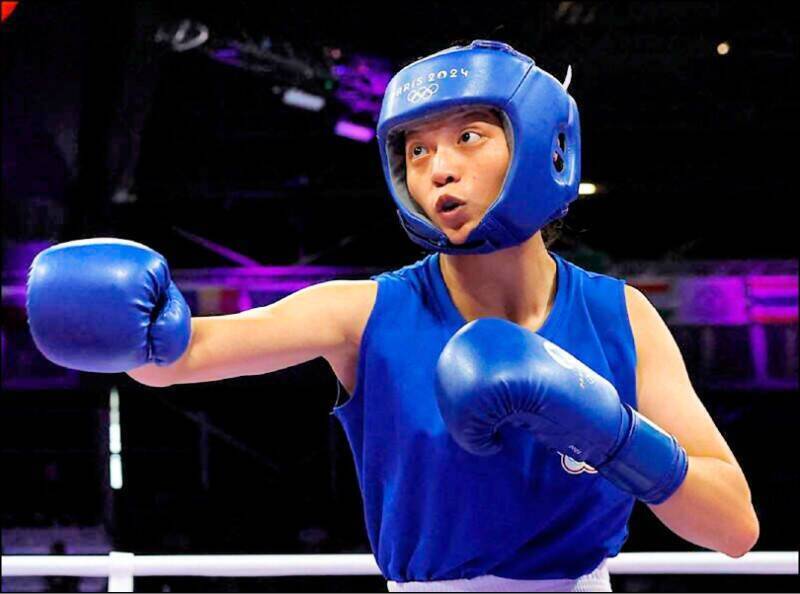 台灣拳擊女將吳詩儀在拳擊賽場上全副武裝出擊，身穿藍色拳擊服與護具，專注揮拳進攻。