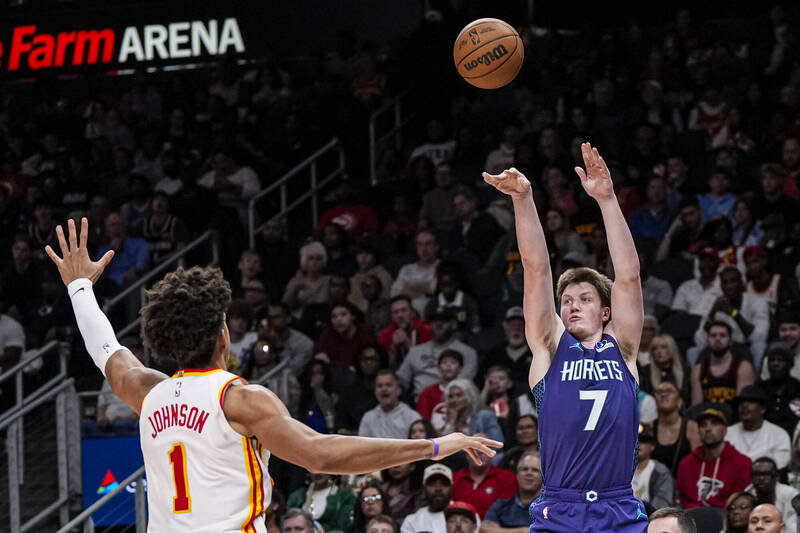 一名身穿紫色球衣的球員在比賽中出手投籃，對位防守者舉手干擾，背景為滿座觀眾的籃球場。