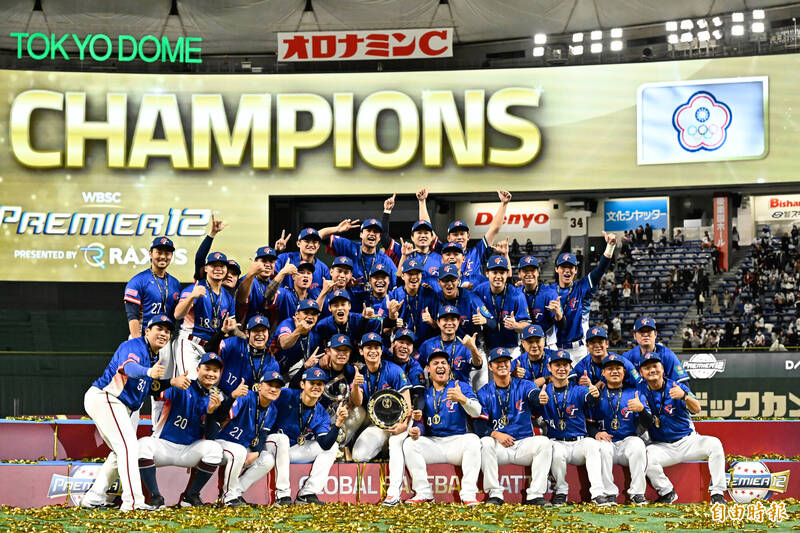 台灣棒球代表隊在東京巨蛋慶祝奪得 12 強冠軍，全隊身穿藍色球衣在金色彩帶中合影，背景巨型螢幕顯示 CHAMPIONS 字樣。