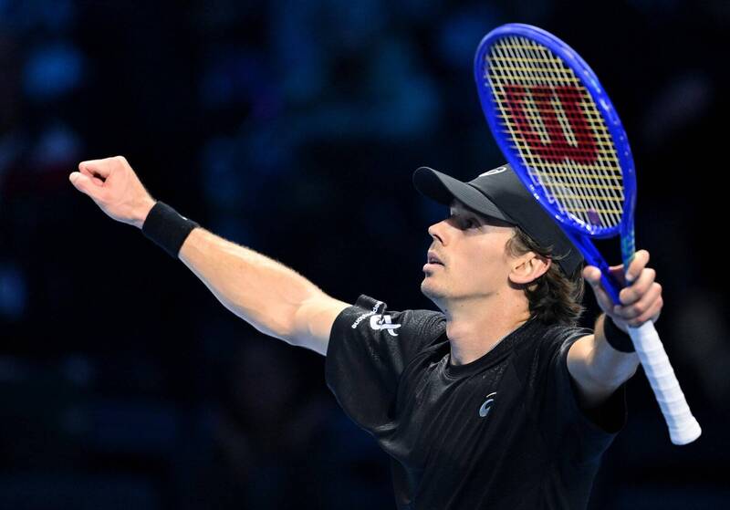 「一名男子網球選手在比賽場上高舉球拍並伸出手臂慶祝得分，神情專注，自信展現勝利姿態。」