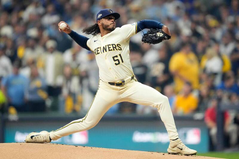 一名棒球投手在比賽中全力投球，身穿淺色球衣於投手丘上出手