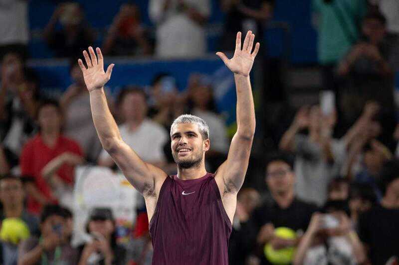 一名網球選手在比賽場上舉起雙手向觀眾致意的畫面