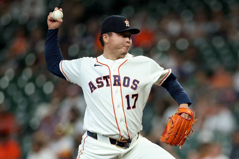 太空人隊台灣強投鄧愷威身穿白底橙邊、胸前繡有「ASTROS 17」字樣的太空人隊經典主場比賽球衣，頭戴深藍色印有橙色「H」隊徽的球帽。他在投手丘上高舉右手棒球準備奮力投出，左手戴著亮橙色棒球手套，眼神充滿殺氣與專注。