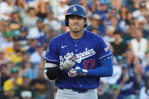 道奇隊球員大谷翔平身穿藍色 17 號球衣、頭戴藍色球盔,神情專注地在球場上調整手套。