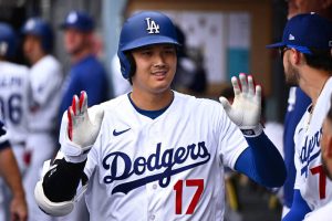 大谷翔平身穿道奇隊白色球衣與隊友擊掌慶祝。