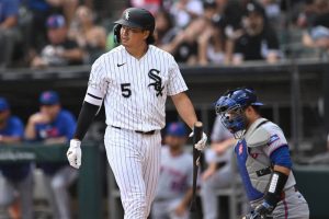 村上宗隆身穿白襪隊 5 號黑白條紋主場球衣在打擊區揮空三振後拿著球棒轉身走回休息區。