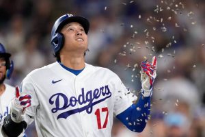 大谷翔平身穿道奇隊 17 號白色球衣在球場上抬頭仰望，身旁散落著慶祝的葵花子。