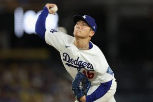 山本由伸身穿道奇隊 18 號白色主場球衣在投手丘上高舉右臂準備投球。