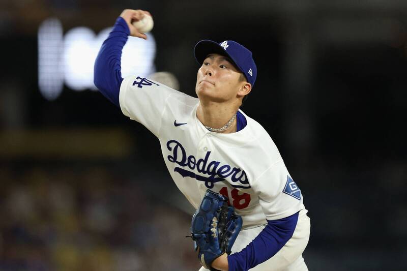 山本由伸身穿道奇隊 18 號白色主場球衣在投手丘上高舉右臂準備投球。